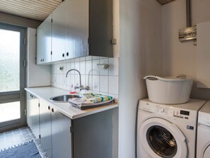 A compact laundry area with a washing machine, a sink, and a drying rack.
