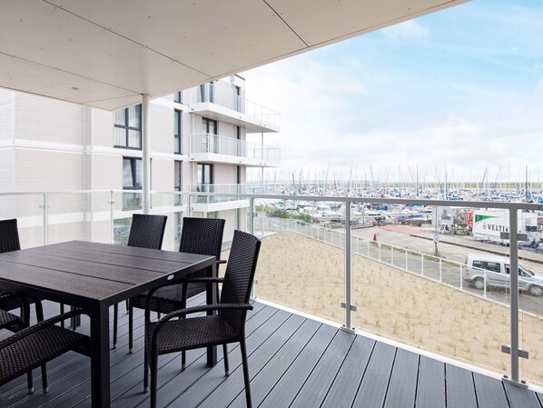 A balcony with a table and chairs overlooking a marina with boats.