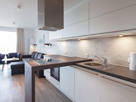 Una cocina moderna con horno empotrado, un lavamanos y un comedor con mesa y sillas.