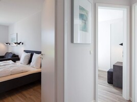 A modern bedroom with a bed, bedside tables, and a wall-mounted light fixture.