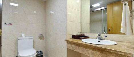 A bathroom with a toilet, sink, mirror, and towel rack.