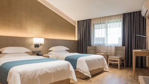 Une chambre d’hôtel avec deux lits, un bureau, une chaise et une lampe.