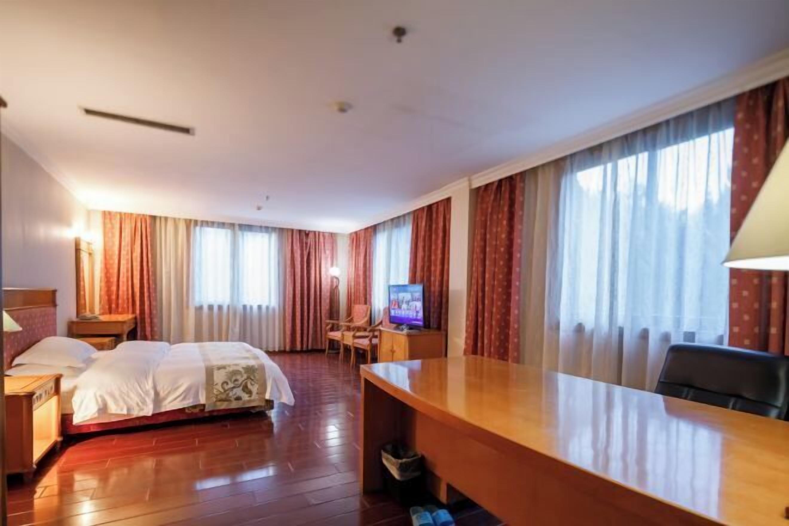 A hotel room with a bed, a desk, a chair, and a television.