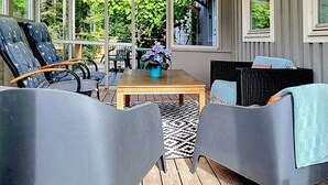 A covered outdoor seating area with two grey chairs, a wooden table, and a potted plant. - 4 Person Holiday Home in Uddevalla (Uddevalla)
