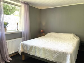 A room with a bed, a window with curtains, a radiator, and a lamp. - 4 Person Holiday Home in Uddevalla (Uddevalla)