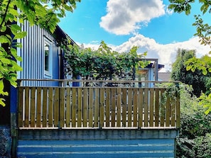 A wooden fence with a view of a blue building and greenery.