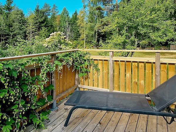A wooden deck with a metal chair and a wooden fence covered in greenery.