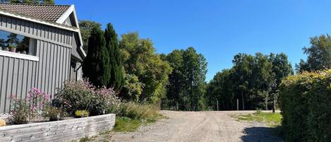 A gravel driveway leading to a wooden building with a sloped roof.