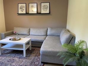 A living room with a grey sofa, a white coffee table, a patterned rug, and three framed artworks on the wall. - 4 Person Holiday Home in Uddevalla (Uddevalla)