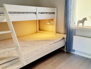 A bunk bed with a ladder, a desk with a lamp, and a window with a view of the outside. - 4 Person Holiday Home in Uddevalla (Uddevalla)