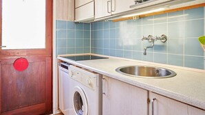 A compact kitchen with a built-in washing machine, a sink, and a microwave. - 4 Person Holiday Home in Aakirkeby (Akirkeby)