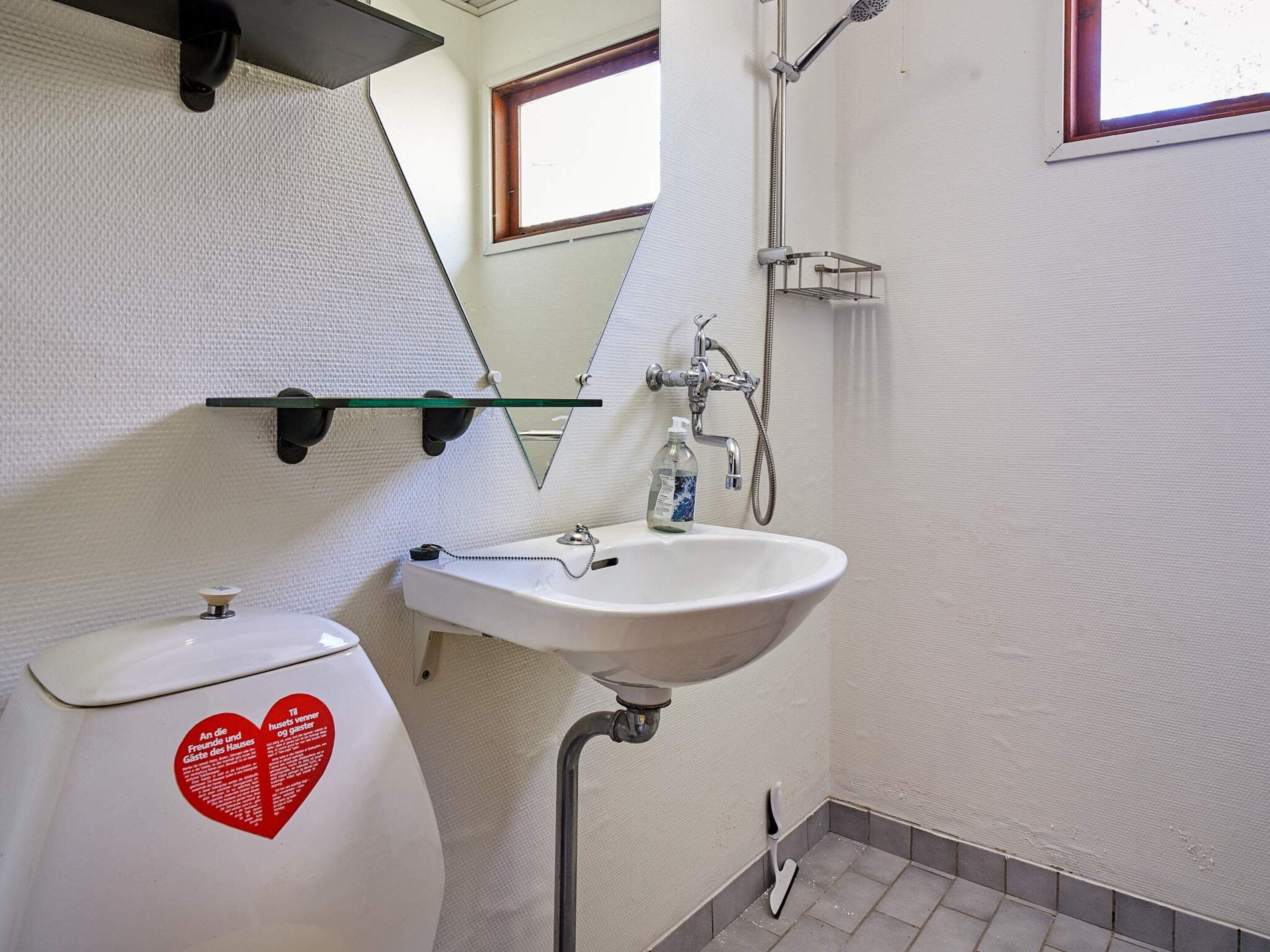 A bathroom with a white sink, a toilet, and a shower.
