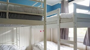 A bunk bed room with white bedding, a checkered floor mat, and a window with curtains. - 6 Person Holiday Home in Stromstad (Stromstad)