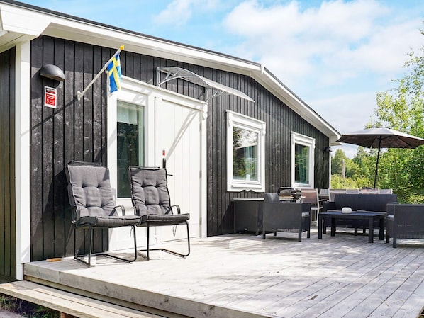 A wooden deck with outdoor furniture, a flag, and a sign on the building.
