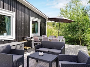 An outdoor patio area with wicker furniture, a grill, and a table with a decorative item.