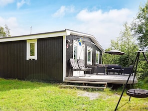 A single-story building with a deck, outdoor seating, and a flag.