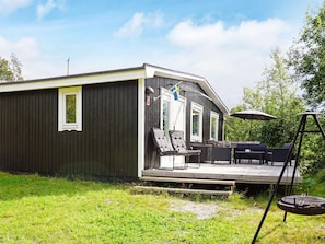 A single-story building with a deck area featuring outdoor furniture and a swing set.