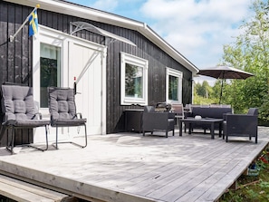 A wooden deck with outdoor furniture, a flag, and a grill.