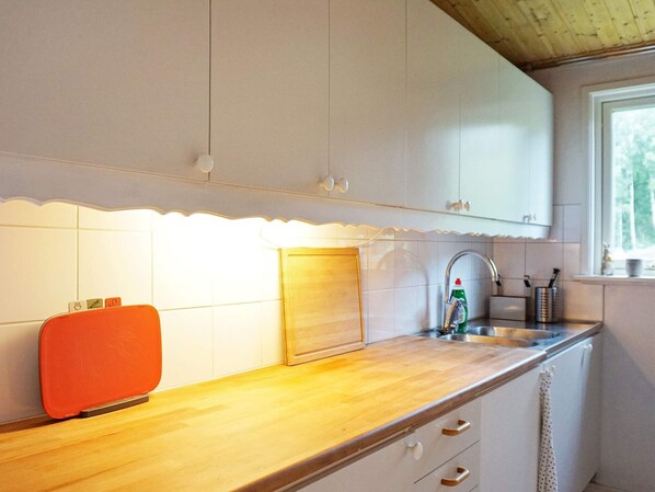 A kitchen with white cabinets, a wooden countertop, a sink, and a window.