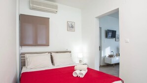 A hotel room with a bed, a bedside lamp, a TV, and a small table with a bowl.