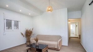 A room with a sofa, a coffee table, a hanging light fixture, and a window.