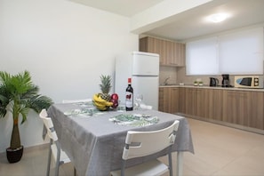 Cozinha compacta equipada com geladeira, micro-ondas e cafeteira.
