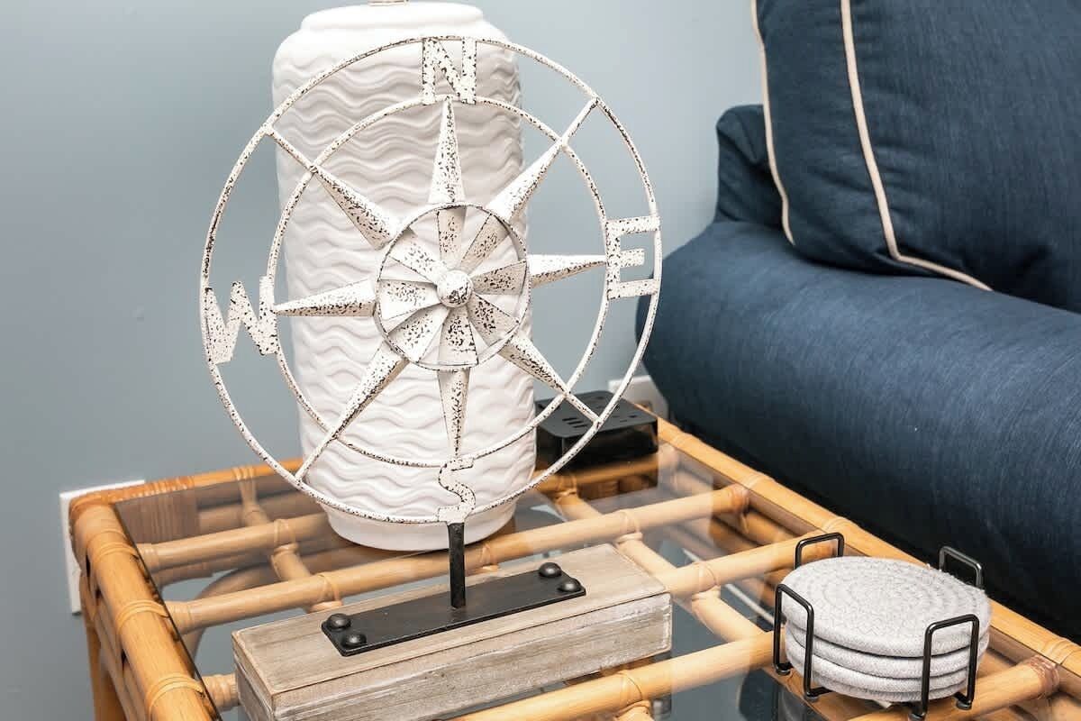 Een decoratieve waaier op een glazen tafel met een kussen en een klein rond voorwerp ernaast.
