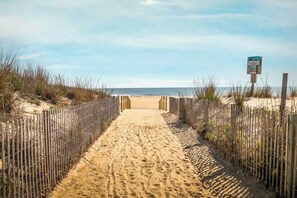 A sandy beach path with a wooden fence on both sides, leading to the ocean. - Ocean City Beach Retreat with Linens Included (Ocean City)