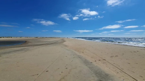 Una platja ampla amb cel serè i mar tranquil·la.