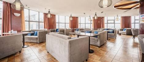 A spacious lounge area with multiple seating options, including sofas and armchairs, arranged around a central coffee table.