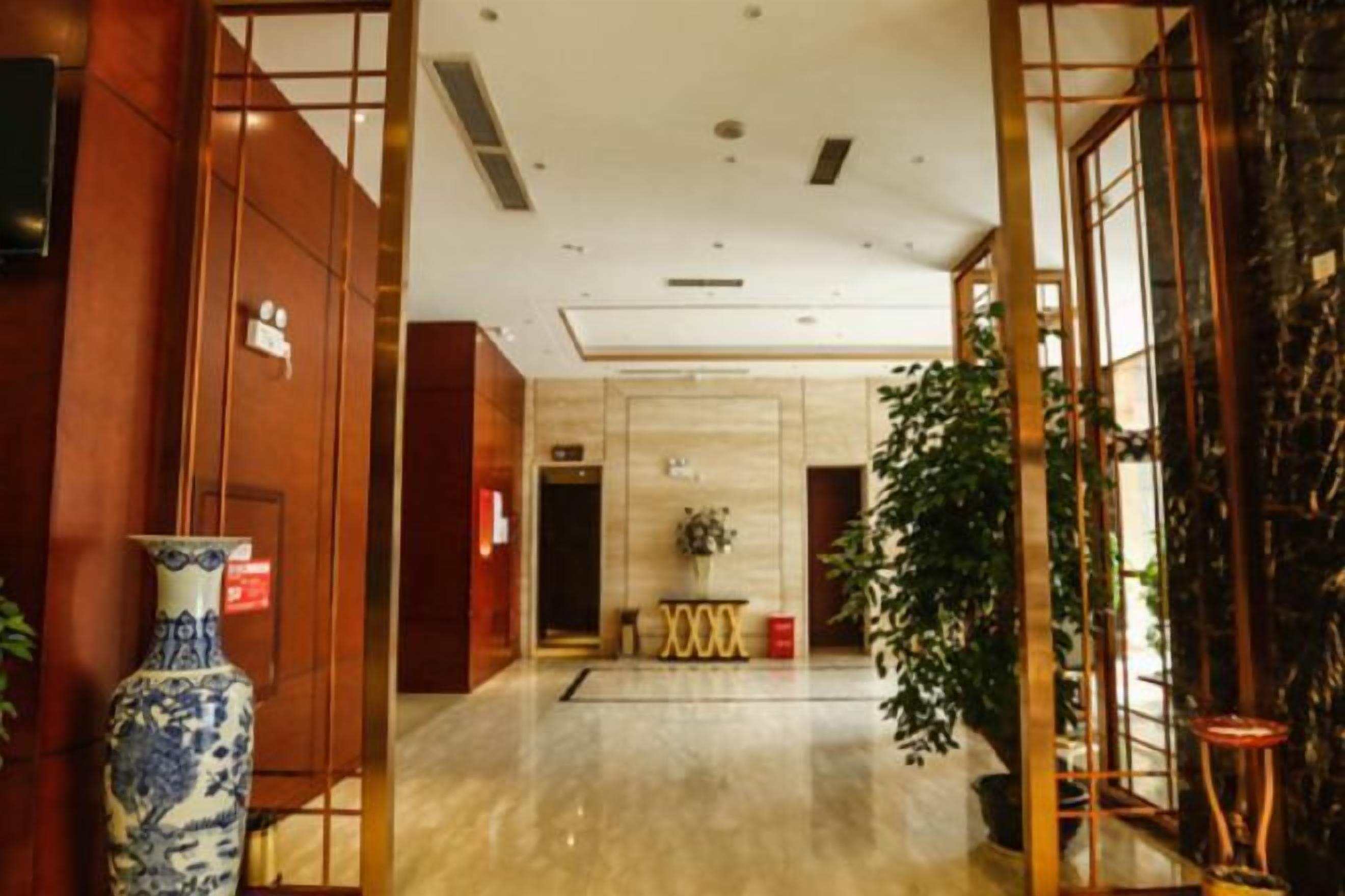 A hotel lobby with a marble floor, wooden paneling, and a large vase on the left.