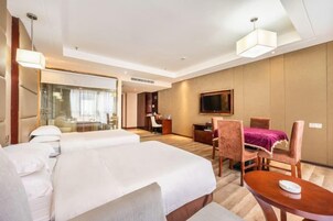 Una habitación de hotel con una cama grande, un escritorio, una silla y un televisor.