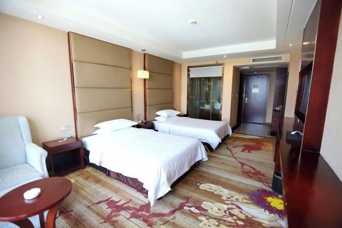 A hotel room with two beds, a sofa, a small table, and a carpeted floor.