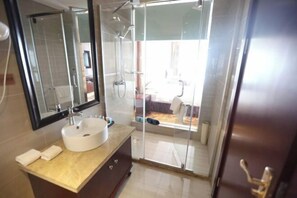 A modern bathroom with a glass-enclosed shower, a white sink, and a large mirror.
