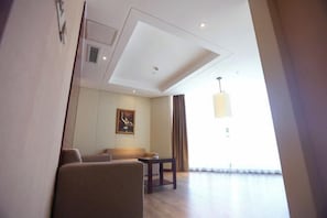 A modern hotel room with a sofa, a small table, and a painting on the wall.