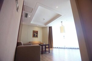 A modern hotel room with a sofa, a small table, and a painting on the wall.