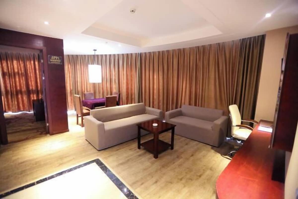 A hotel room with a living area featuring two sofas, a small table, and a desk with a chair.
