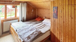 Un lit simple dans une pièce aux murs en bois et au plafond en pente.