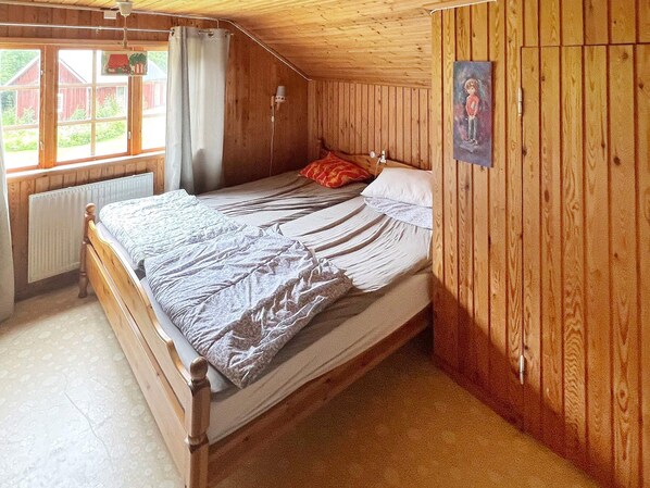 A single bed in a room with wooden walls and a sloped ceiling.