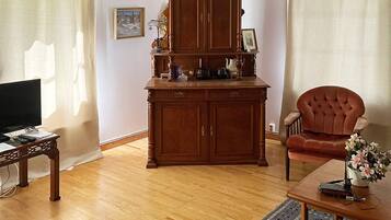 Una sala de estar con un aparador de madera, un televisor, una silla y una mesa de centro.
