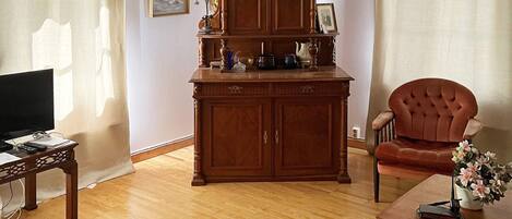 A living room with a wooden cabinet, a television, a chair, and a coffee table.