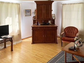 A living room with a wooden cabinet, a television, a chair, and a coffee table.
