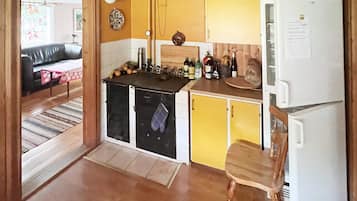 A compact kitchen with yellow cabinets, a white refrigerator, and a wooden chair.