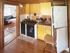 A compact kitchen with yellow cabinets, a white refrigerator, and a wooden chair. - 7 Person Holiday Home in Algaras (Älgarås)