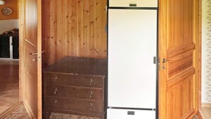 Une pièce avec une armoire en bois, un réfrigérateur blanc et une porte en bois.