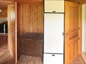 A room with a wooden wardrobe, a white refrigerator, and a wooden door. - 7 Person Holiday Home in Algaras (Älgarås)