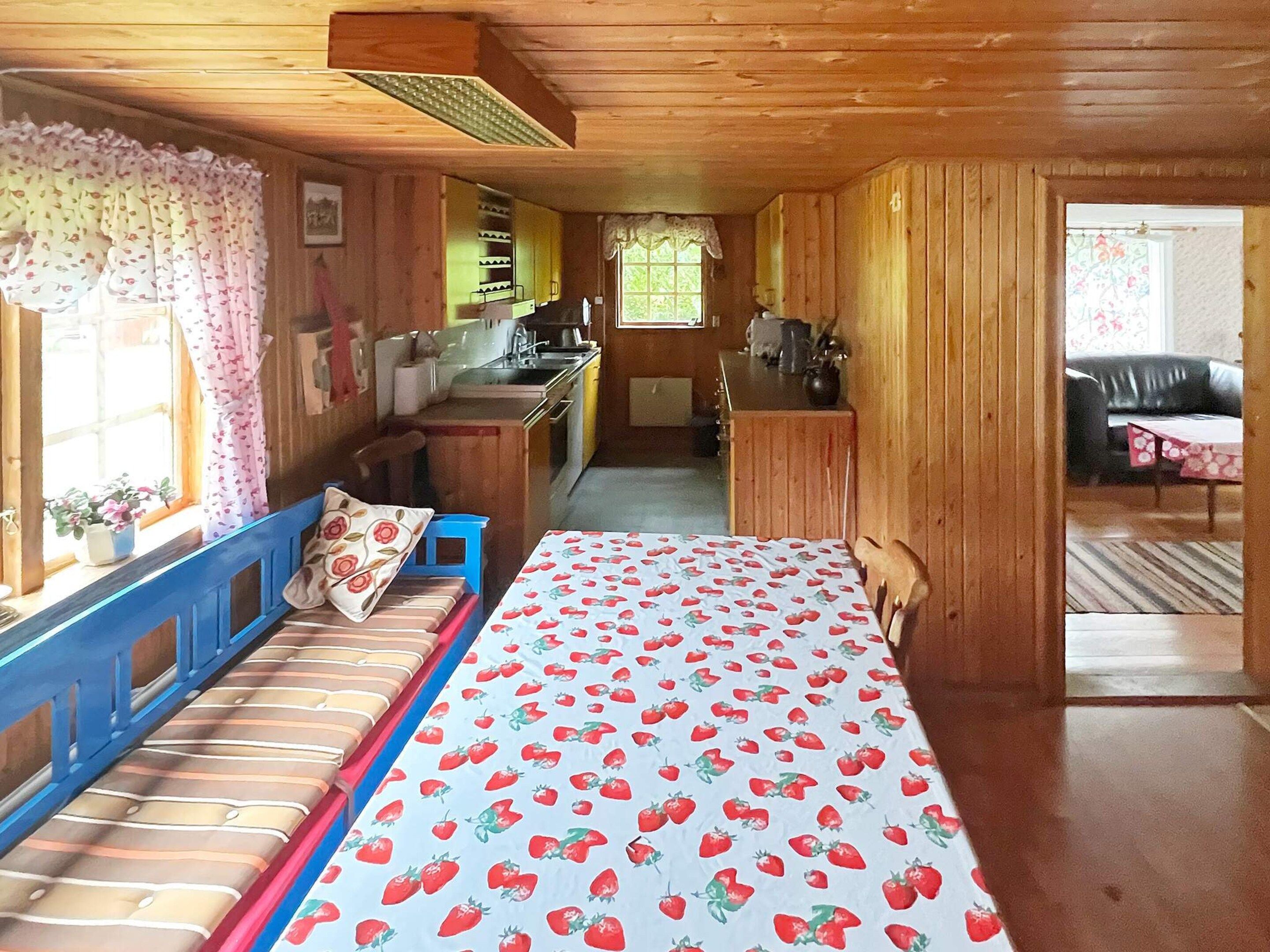 A cozy cabin interior with a bed, a kitchenette, and a dining area.