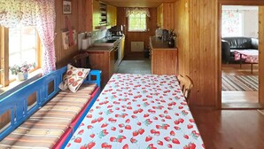 Un intérieur de chalet chaleureux avec un lit, une kitchenette et un coin repas.