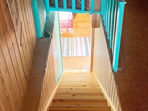 A wooden staircase with a view of a patterned rug and a red object in the background. - 7 Person Holiday Home in Algaras (Älgarås)