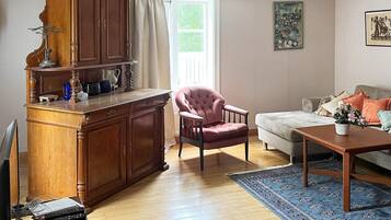 A living room with a wooden cabinet, a pink armchair, a sofa, and a coffee table.